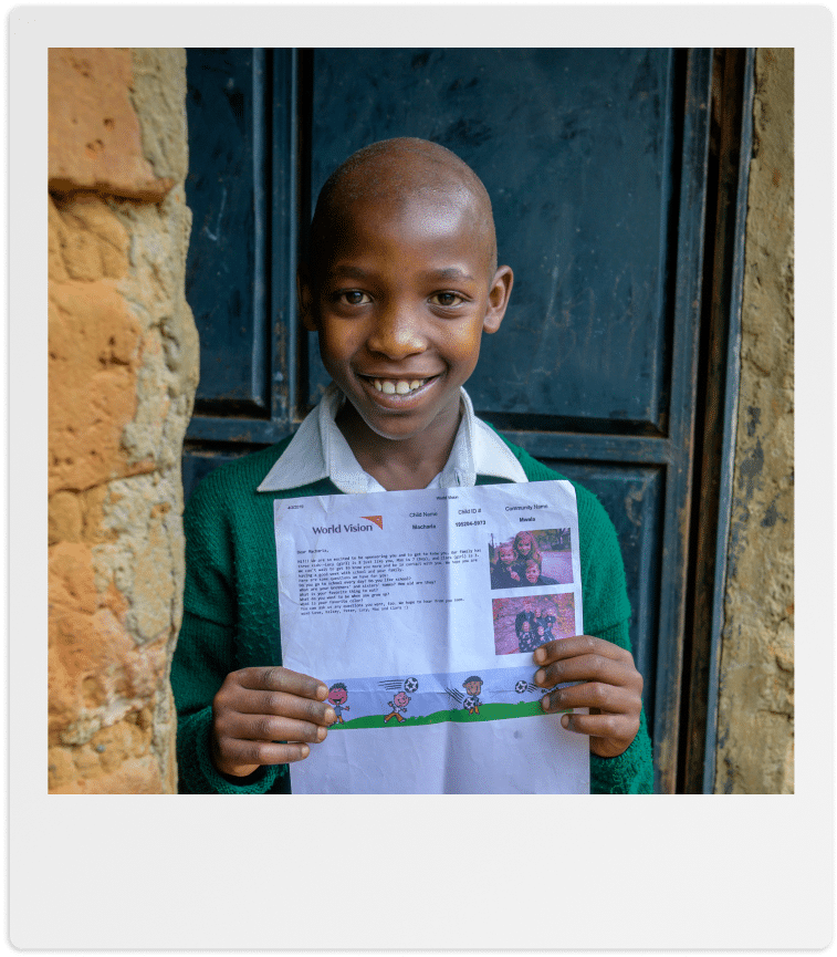 Bambino sorridente che mostra una lettera di World Vision